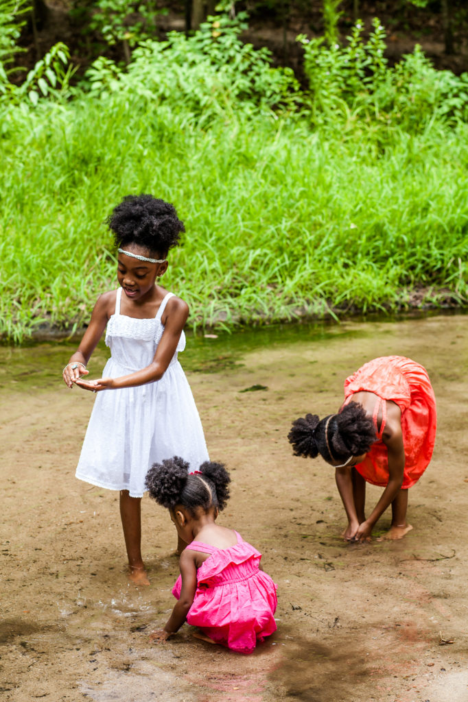 three little black girls playing in a stream